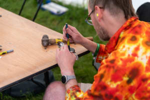A man works with a punch on a titanium spork.