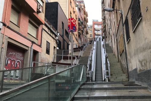 A photo looking up a steep street / alley in Barcelona. There’s an open-air escalator in the middle and steps either side.