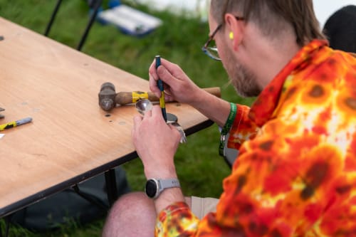 A man works with a punch on a titanium spork.
