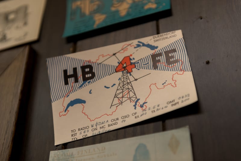 A close macro photo of a vintage radio postcard. The postcard reads “HB 4 FE” and depicts a radio mast giving off signals inside an outline Switzerland.
