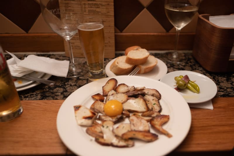 A plate of fried mushrooms with an unbroken egg yoke in the centre.