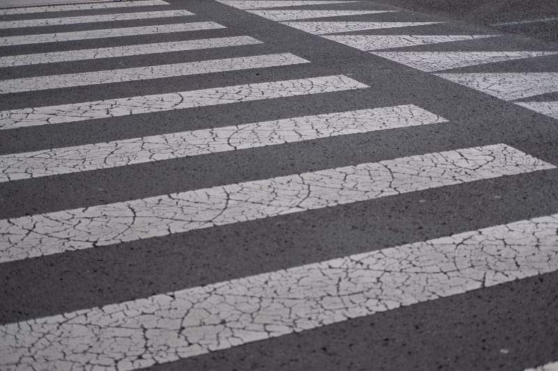 Cracked white markings on tarmac. They’re in a regular grid pattern with arrows at one end.
