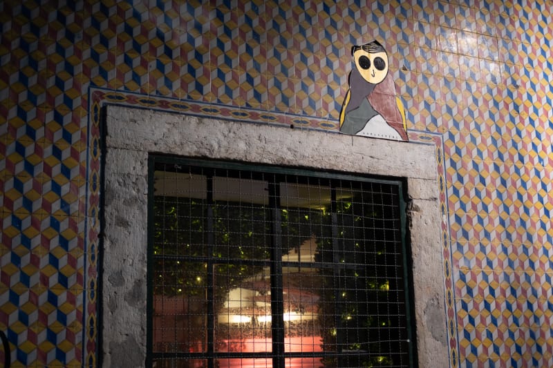 A photo of the top of an exterior window. The wall has a small decorative tile pattern and a graphic of a small person is stuck on the top right of the window.