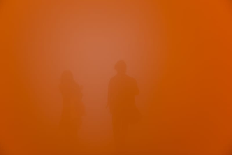 A deep orange frame with no distinct features. Two bodies can just be seen in the background.