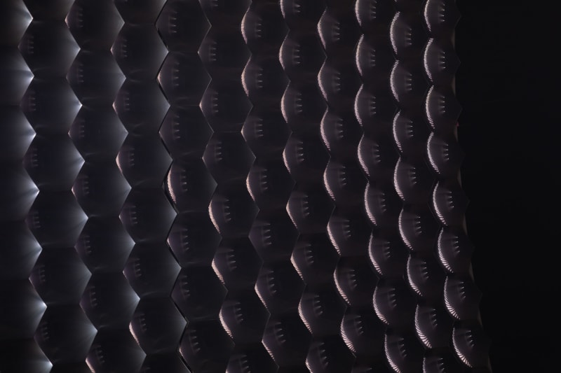 A close crop of what looks like a large multi-faceted glass lens or many small mirrors.