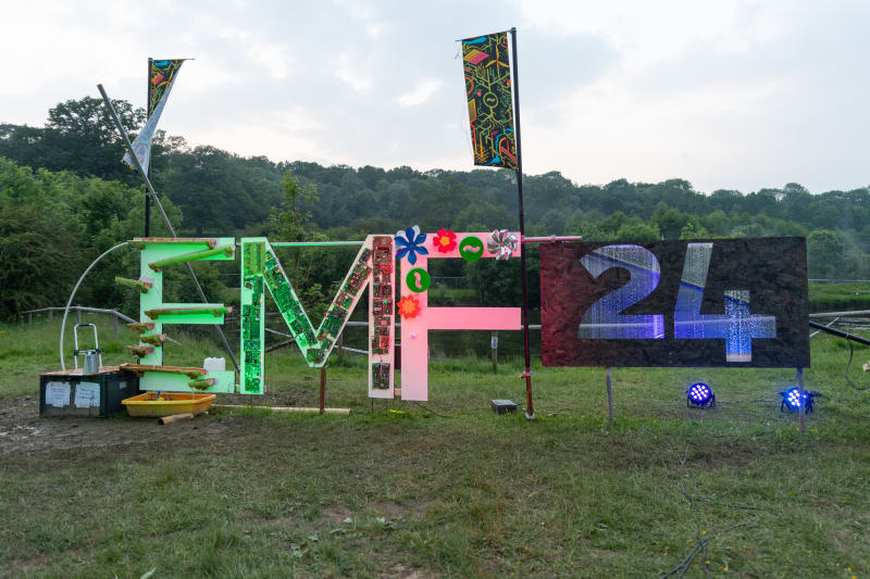 The EMF camp 2024 sign in daylight.