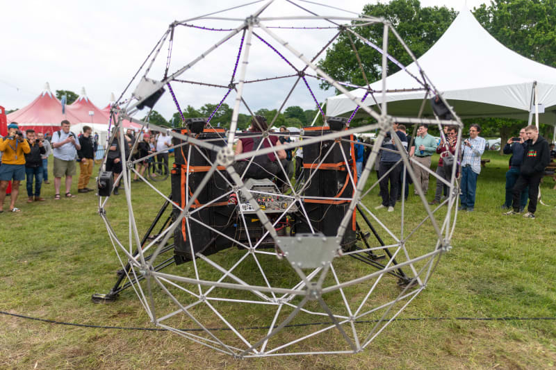 Large geodesic sphere in front of a robotic machine