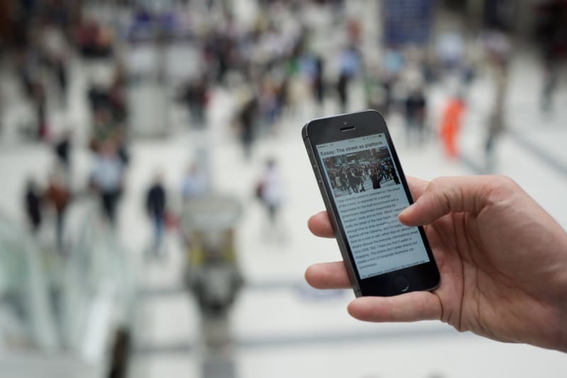 Photo of a hand holding a smartphone, which is showing a web article.