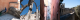 A grid of 4 images in a 4 by 1 layout. From left to right, top to bottom, the images are:
Image 1: A peacock looks stood side on looks at the camera. It’s stood in the shade of a peach pastel coloured building.
Image 2: Looking up at the ruins of the Carmo Convent. All that remains are the arches of the building, with blue sky where the ceiling would be.
Image 3: Looking up a narrow alleyway filled with two flights of steps. The buildings on each side are painted in light pink pastel colours
Image 4: Looking down a series of regular castle battlements. A large olive tree as tall as the battlements is visible on the right.