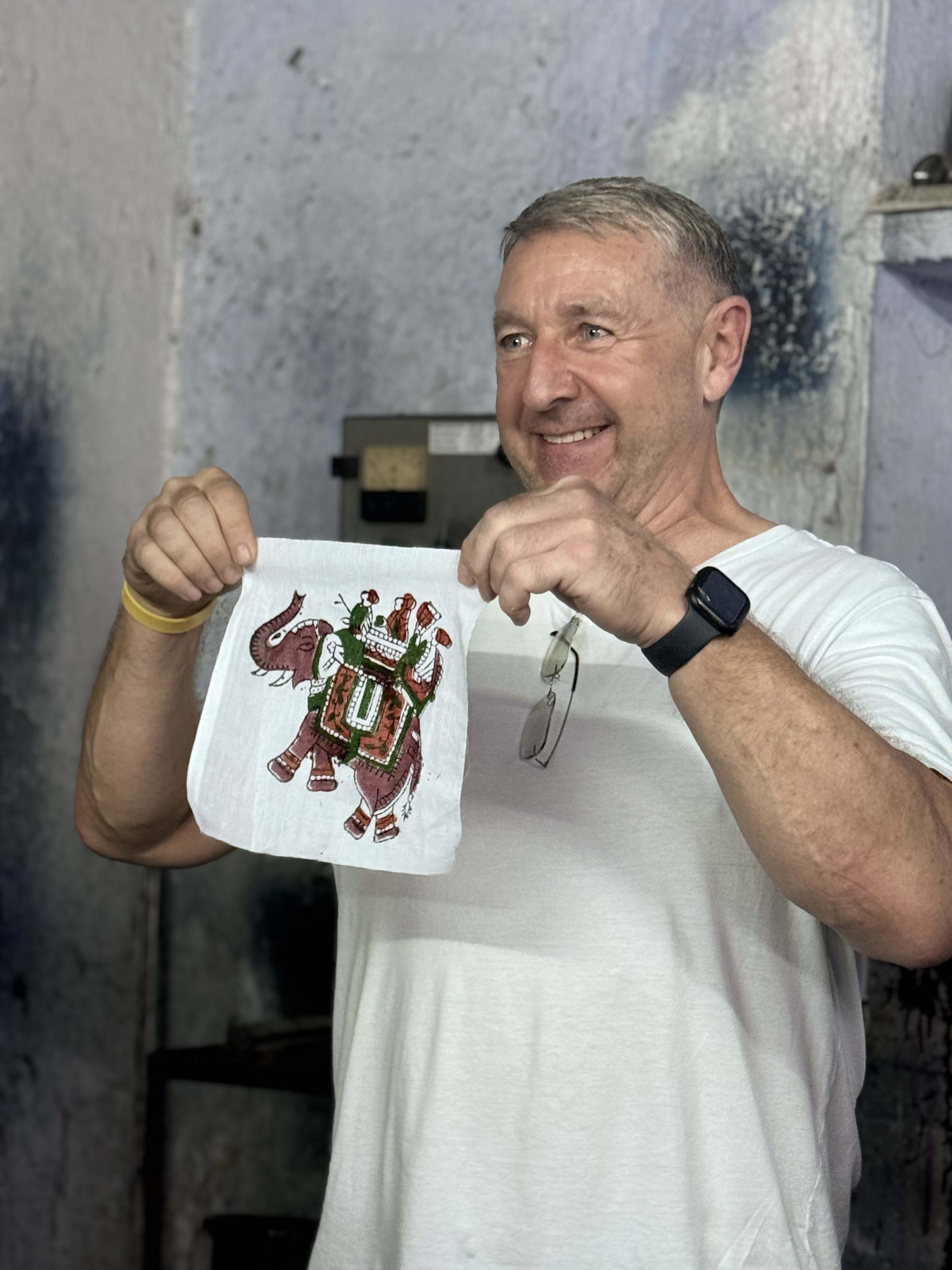 A traveller holding up a block-printed elephant cloth