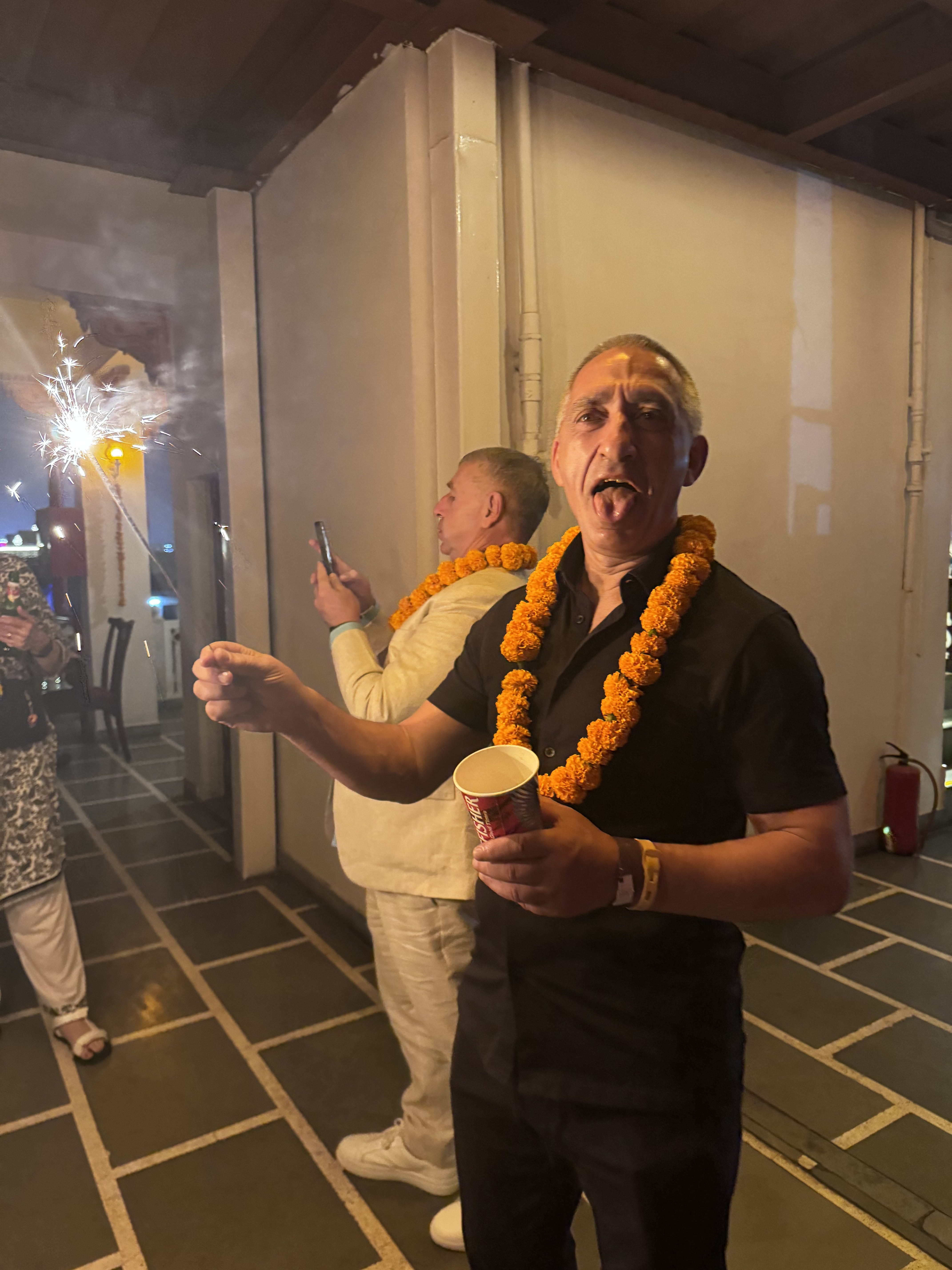 A garlanded traveller at an evening celebration