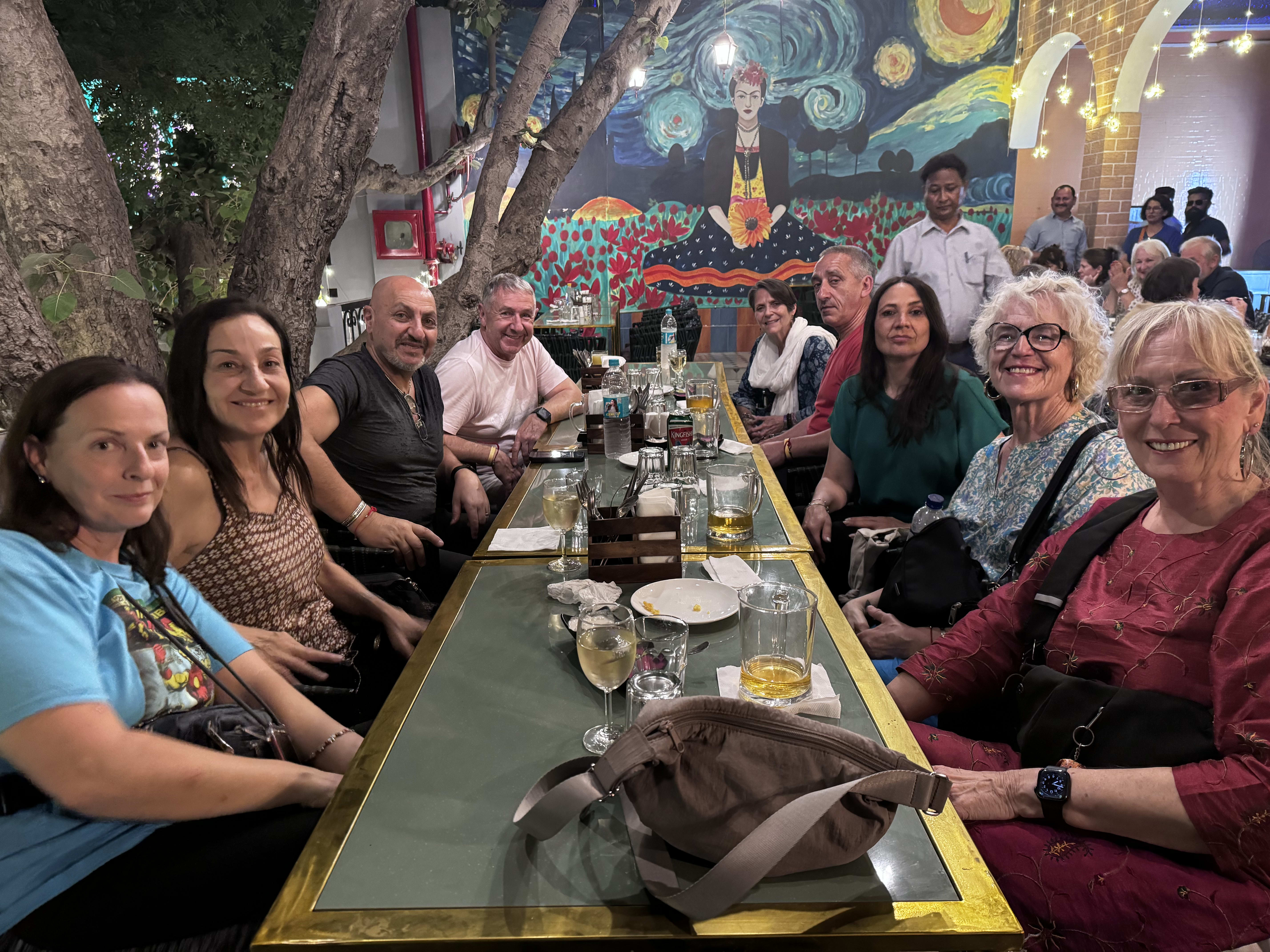 Travellers sharing a meal at a long table in a colourful restaurant