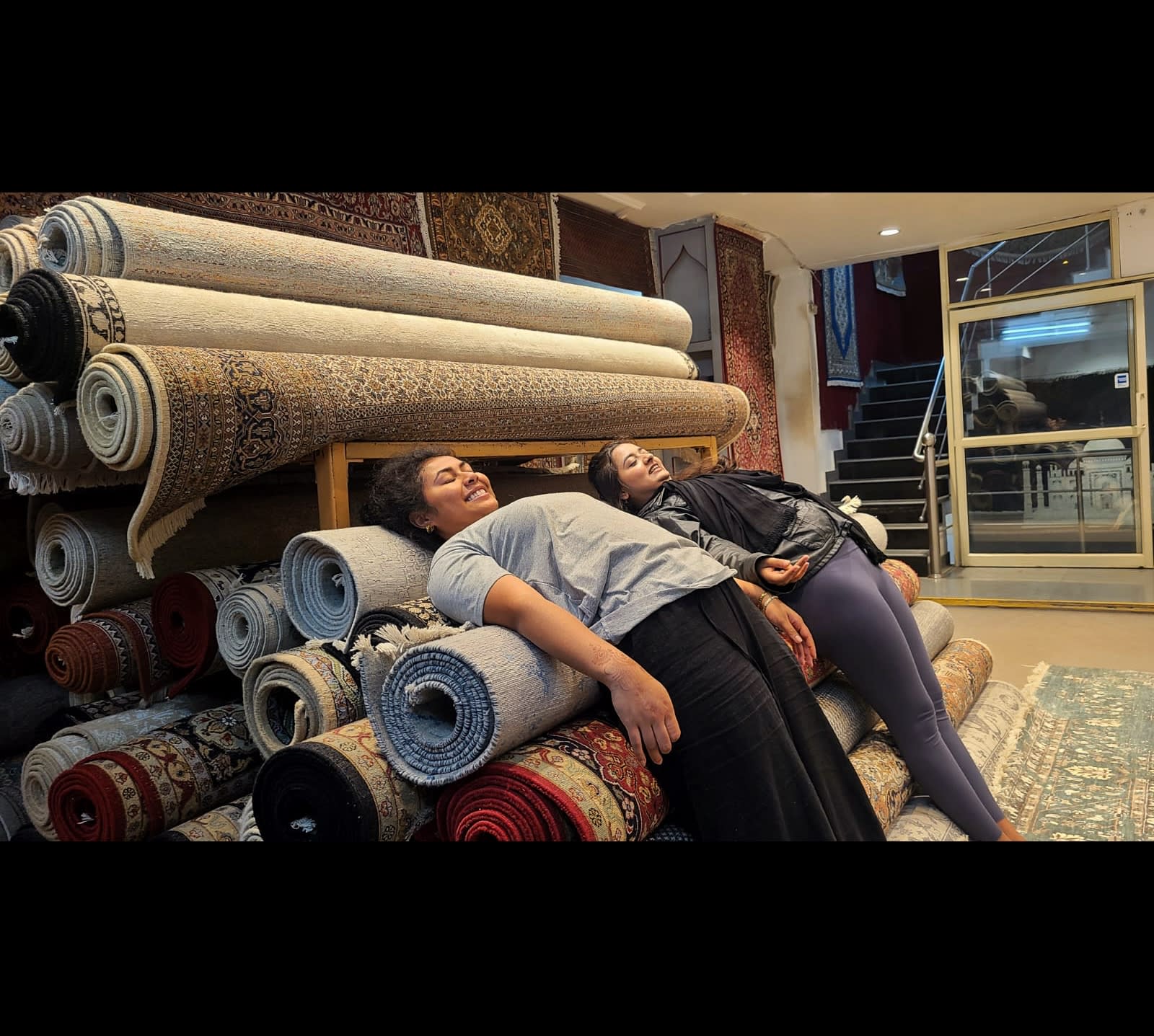 Travellers resting on a stack of rolled carpets in a showroom