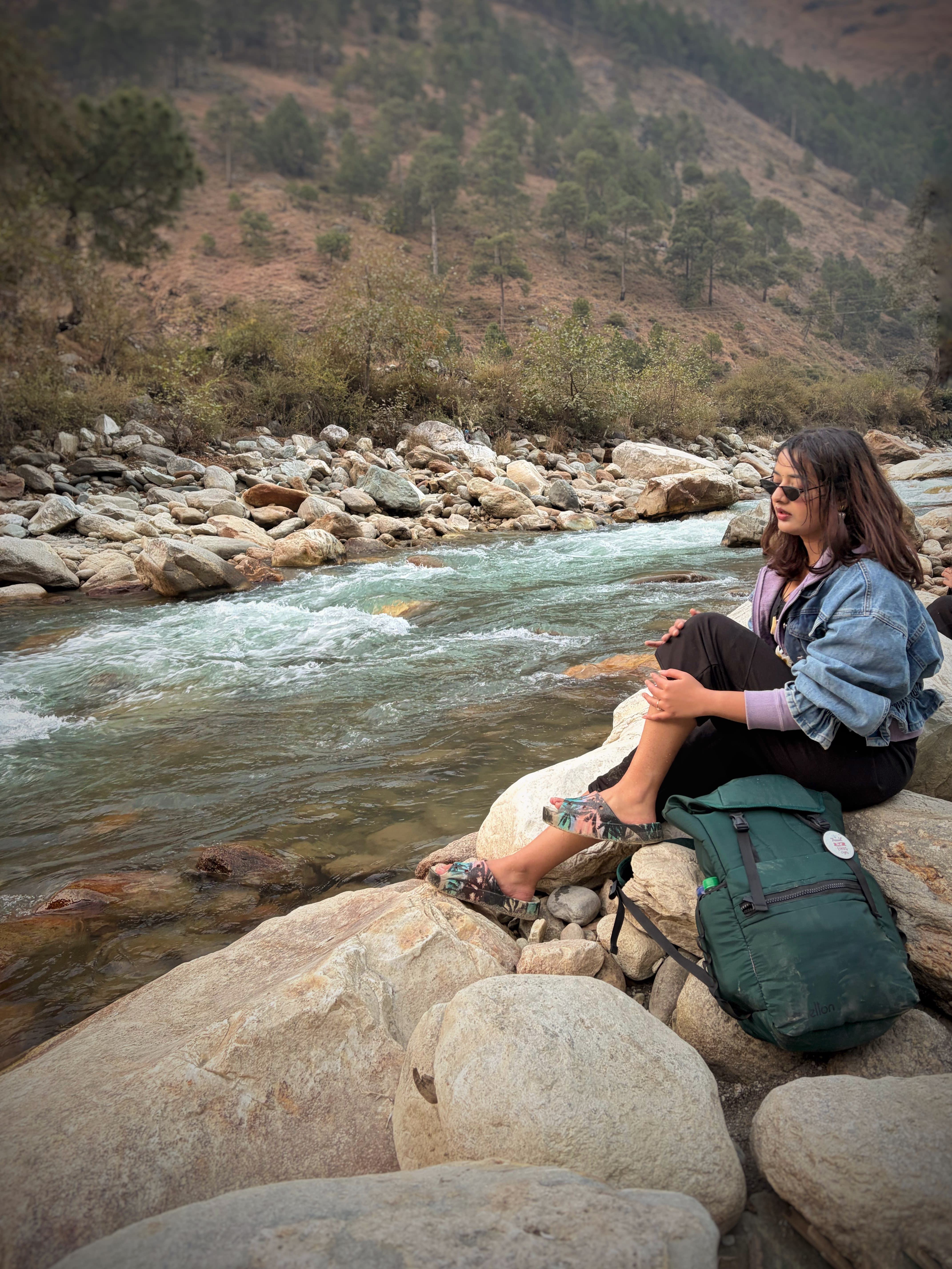 A traveller resting on rocks beside a fast Himalayan river