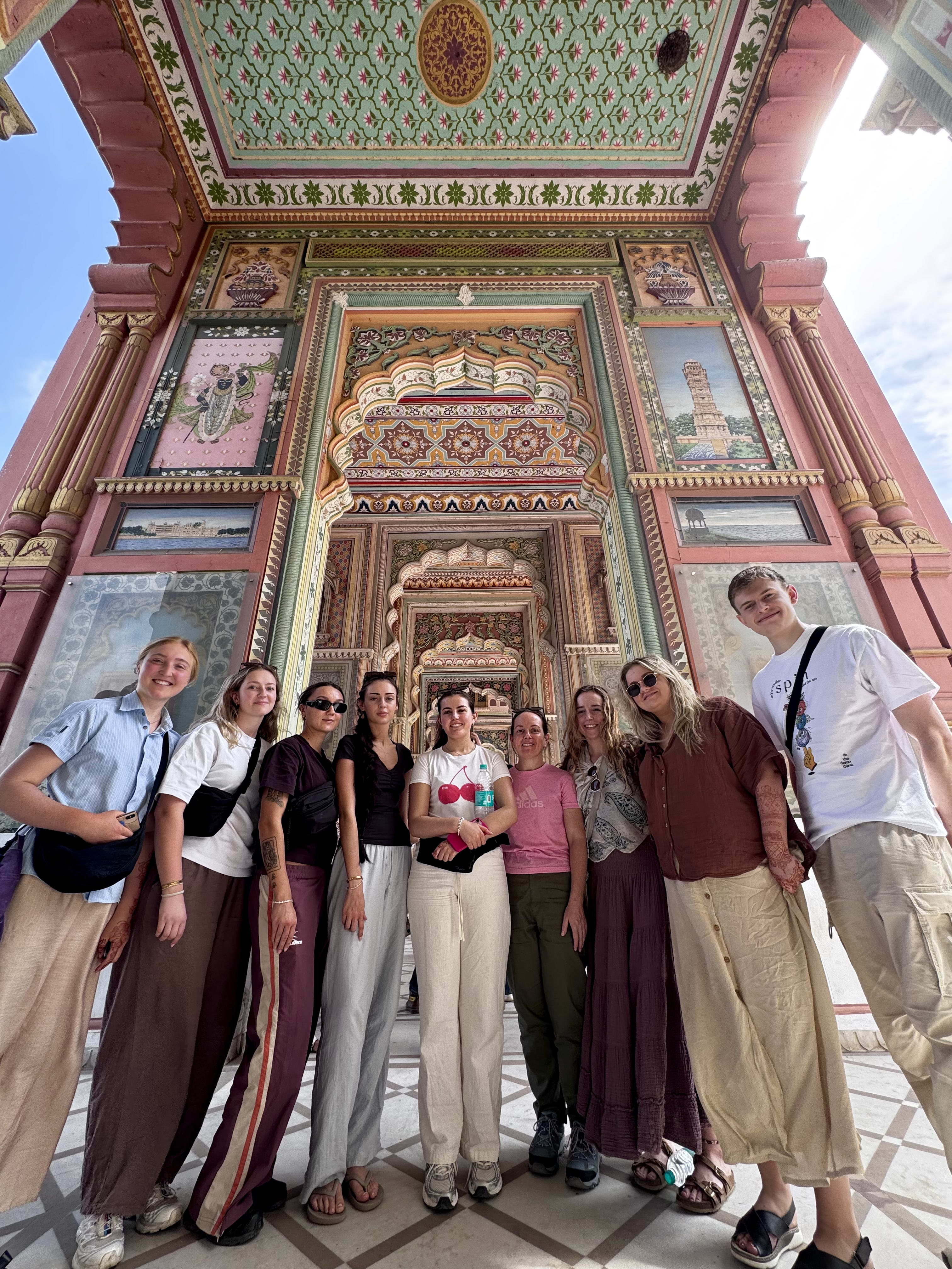 A group of travellers in front of a painted haveli gateway