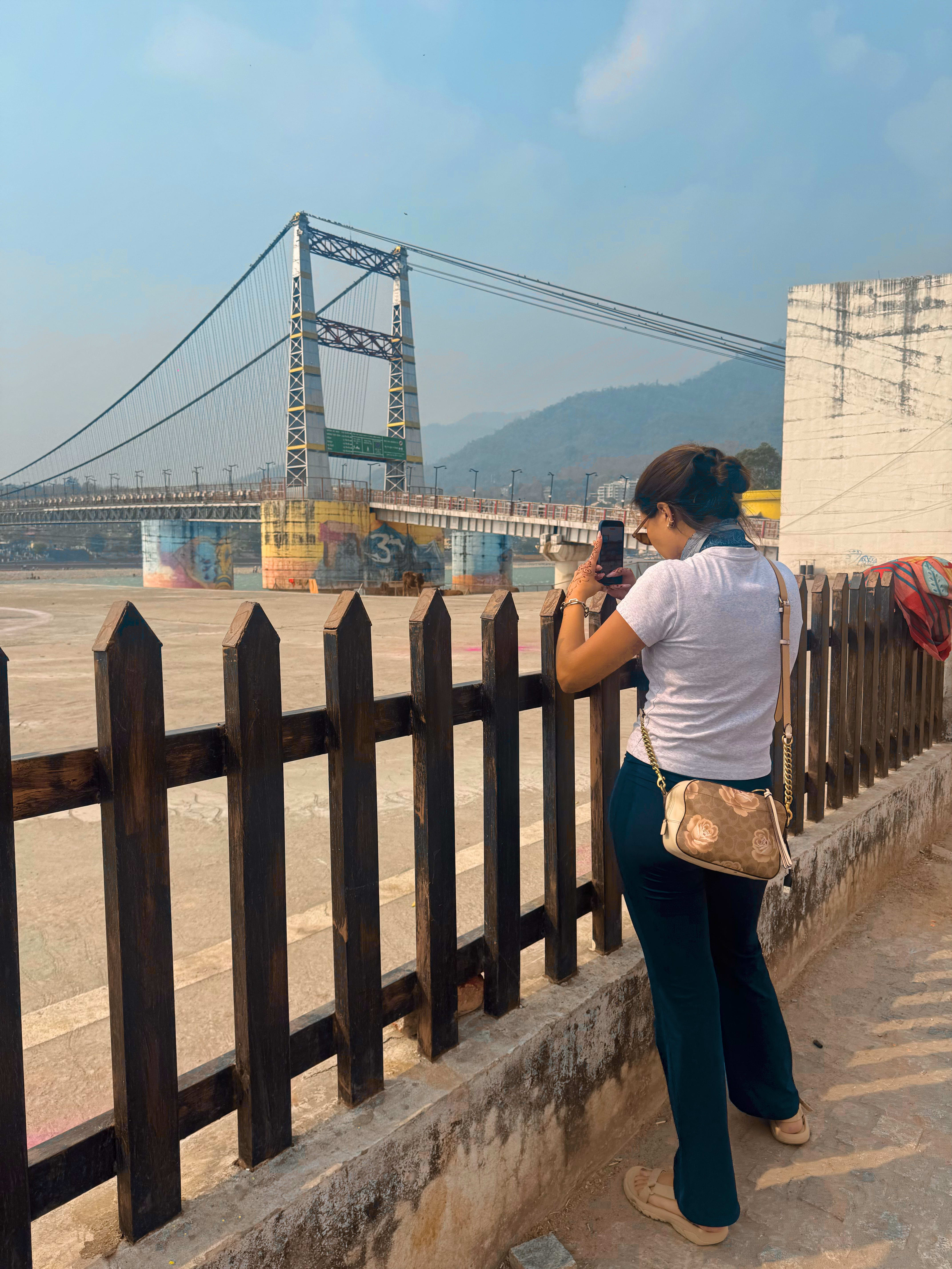 A traveller photographing the suspension bridge over the Ganges at Rishikesh