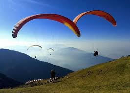 Paragliders soaring over the green hills at Bir Billing