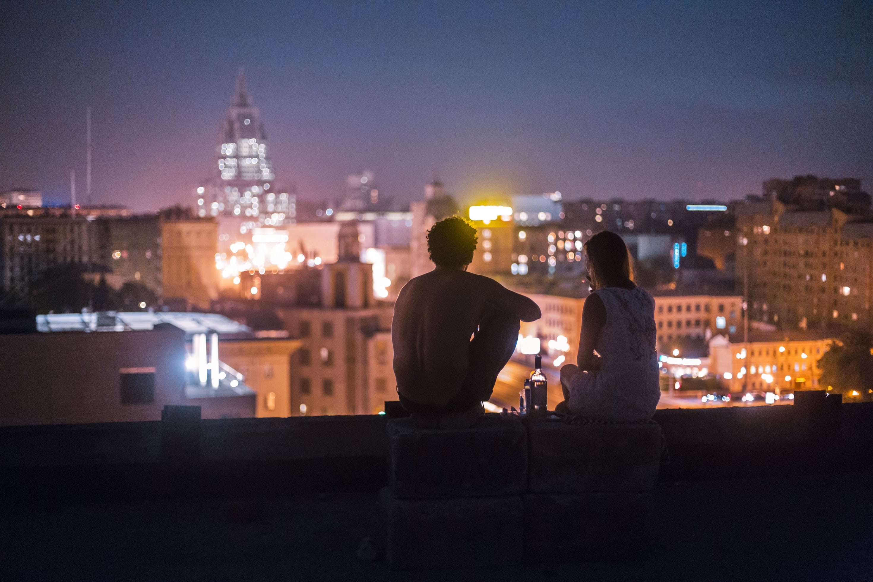 A couple on a rooftop on a date in conversation in the dark