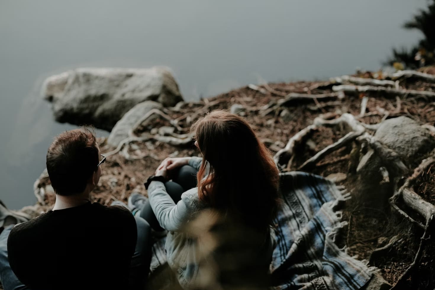 A couple seen from the back chatting together next to a lake