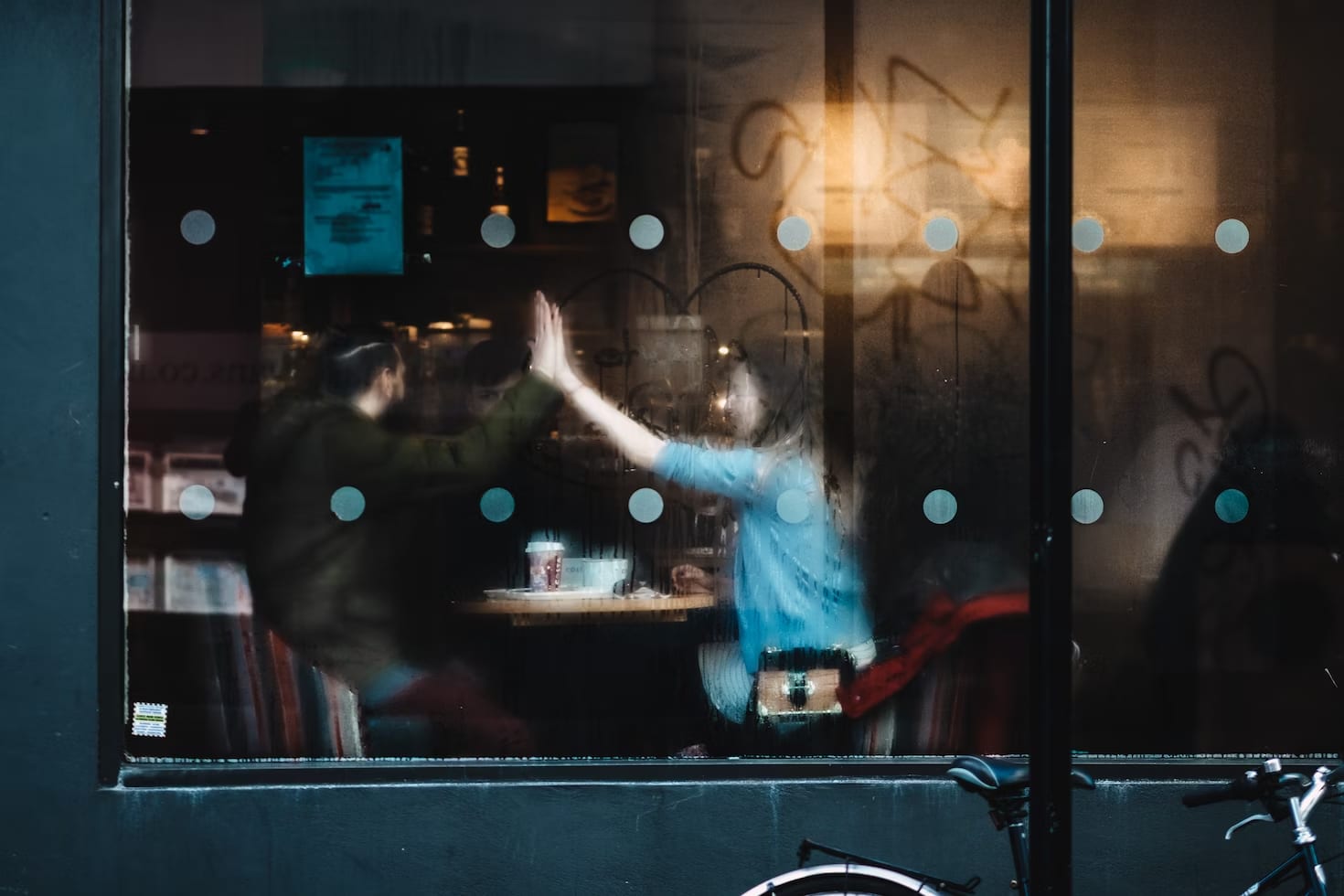 A couple seen through a foggy window as they clap their hands together for a high five