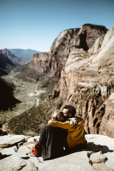 A couple sitting on a mountain hugging