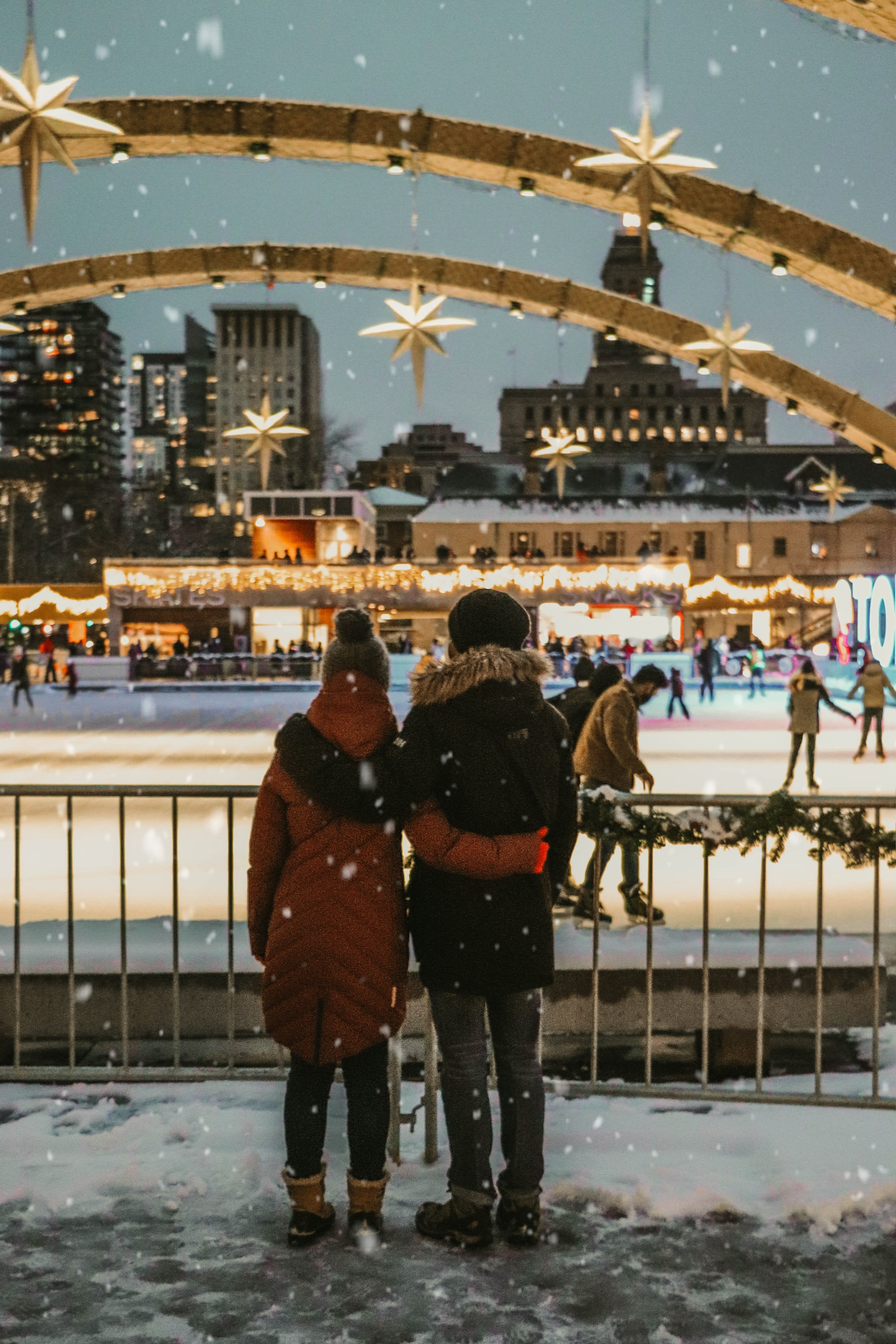 A couple in winter cuddling in front of an ice rink