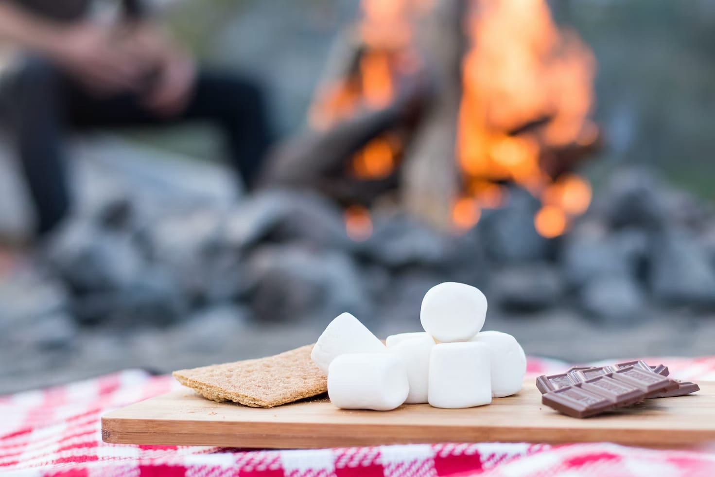 Crackers, marshmallows and chocolate for the perfect some, with a campfire in the background