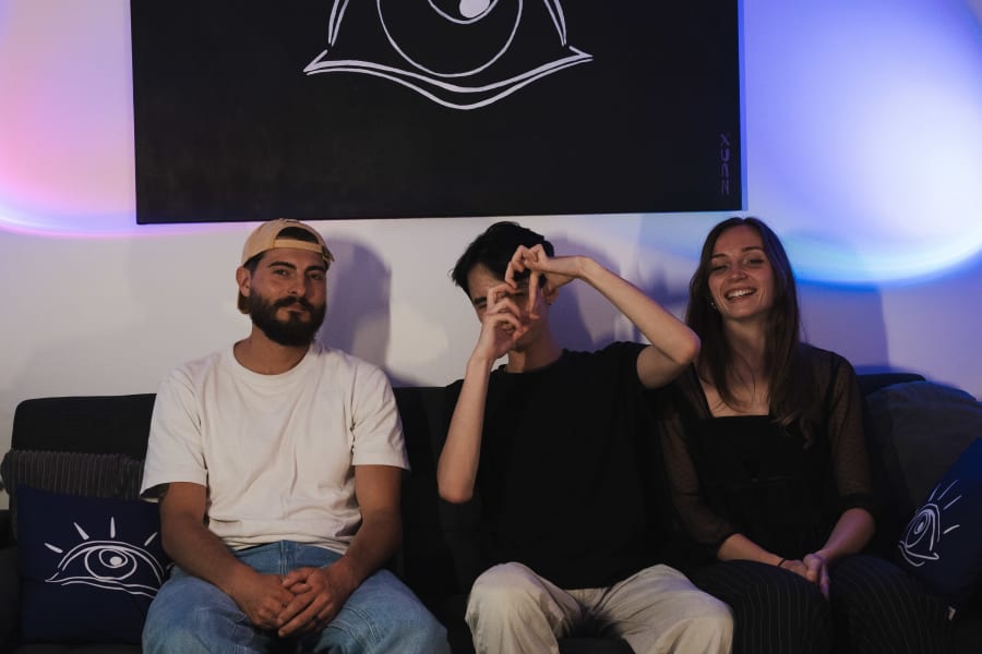 Trois personnes sur le canapé du studio Neuvième Vision, sous la bannière à l’œil