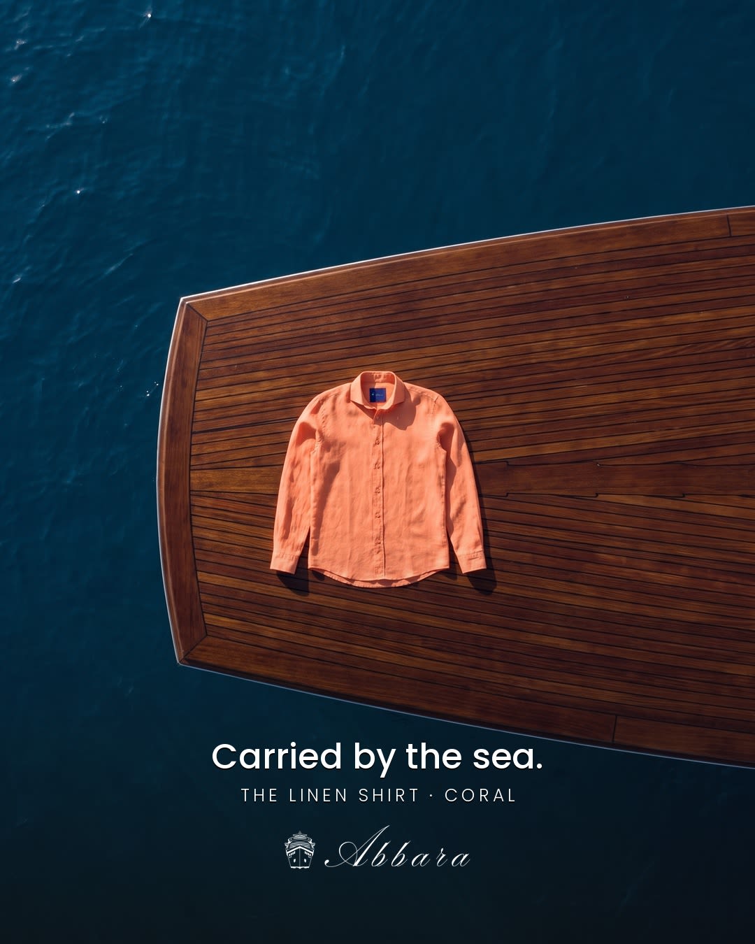 Coral linen shirt on a wooden yacht deck surrounded by blue water