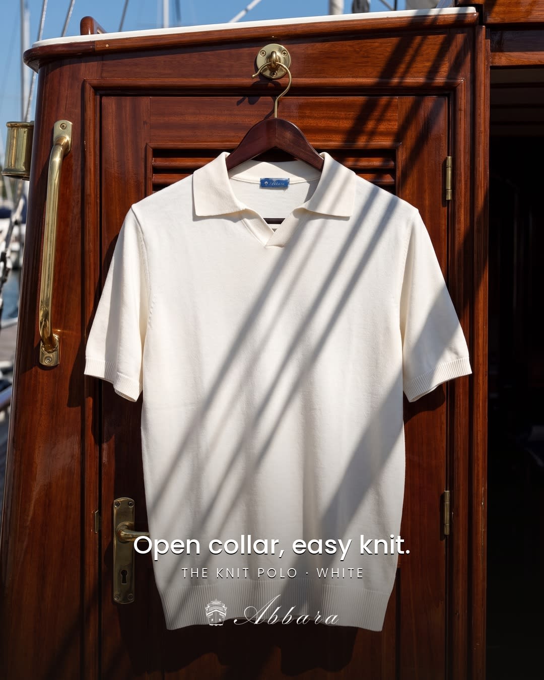 White knit polo hanging on the polished wood of a yacht