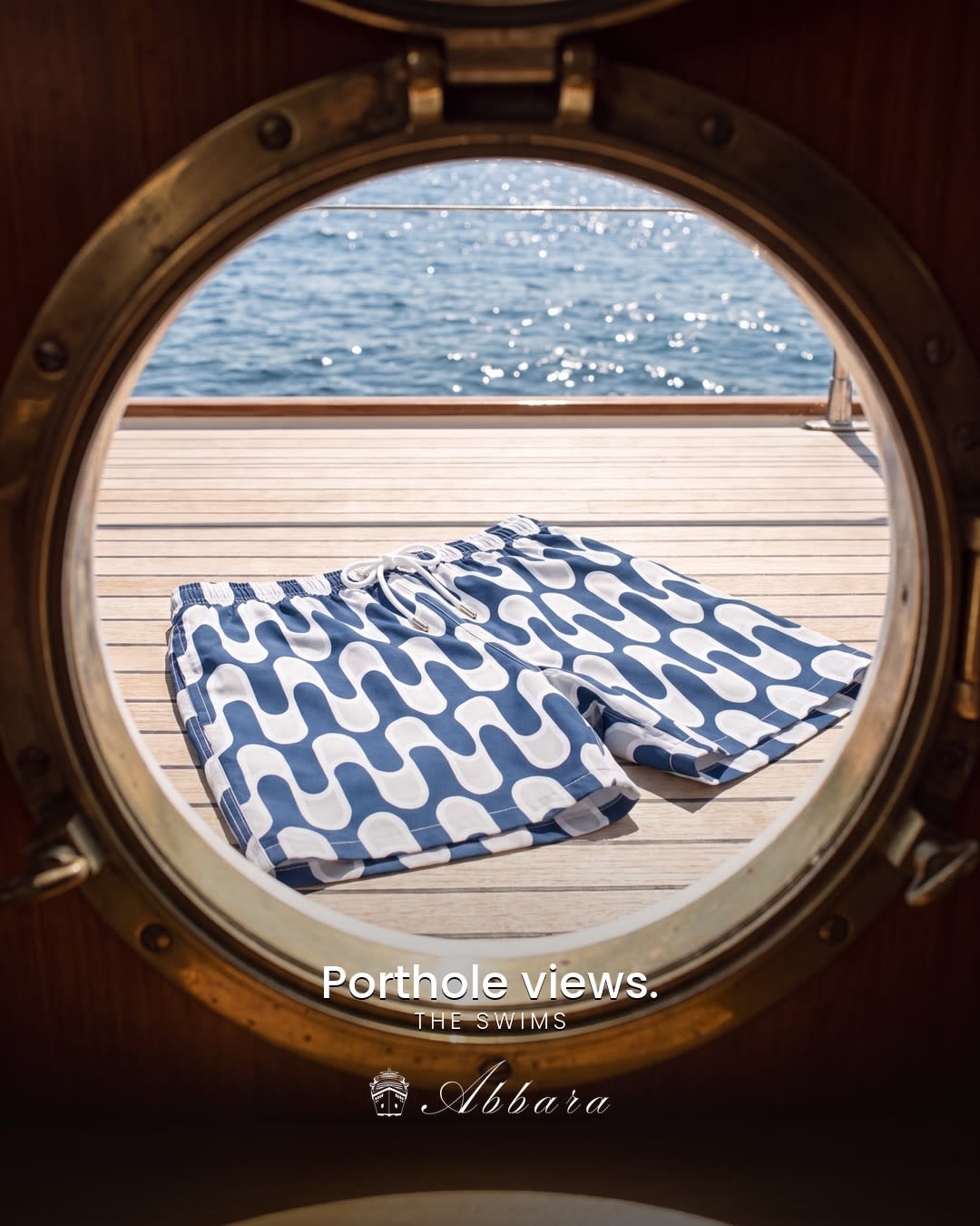 Patterned swim shorts framed by a yacht porthole