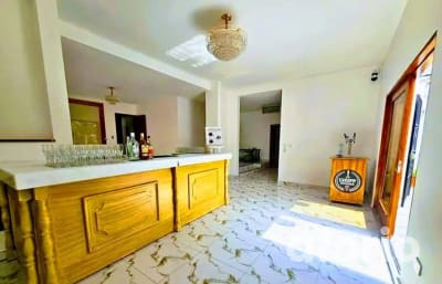 Salón interior con barra de madera y copas servidas, dispensador de chopp y araña de cristal sobre piso de mármol