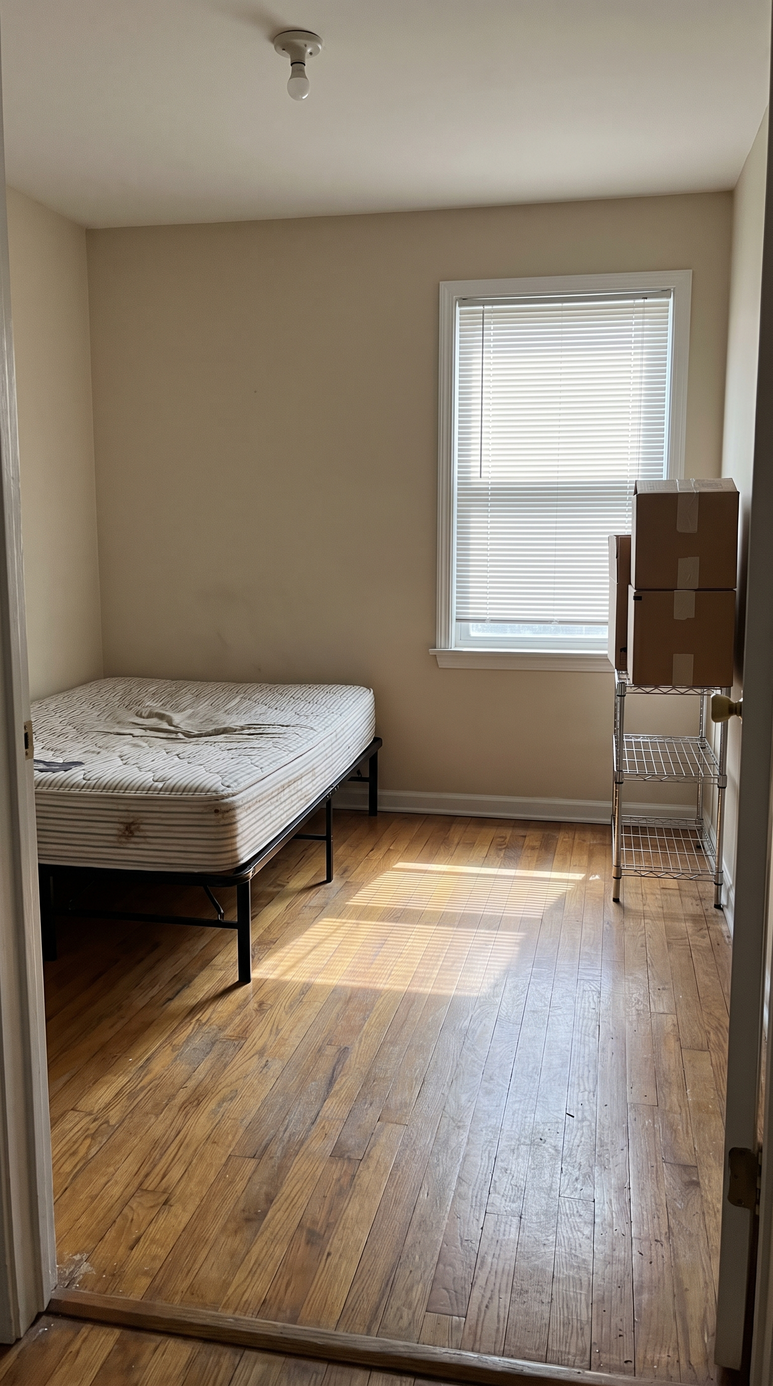 Before: an empty beige rental bedroom with a bare bed frame and no styling