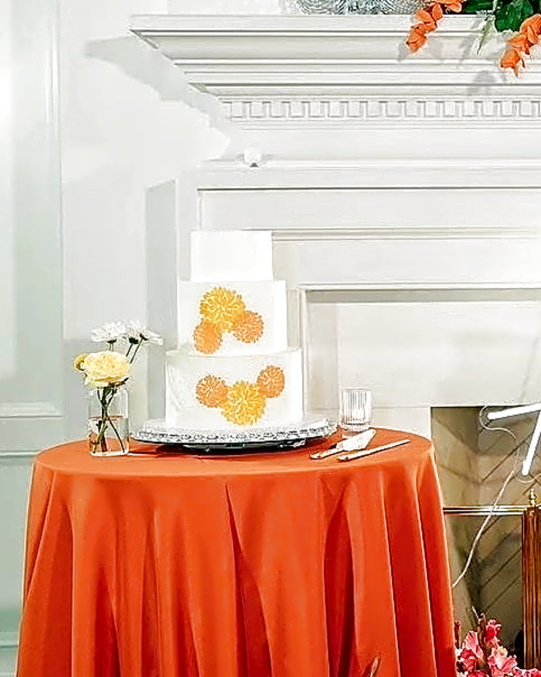 Twenty & Creek wedding cake, two-tier white cake with orange floral stenciling