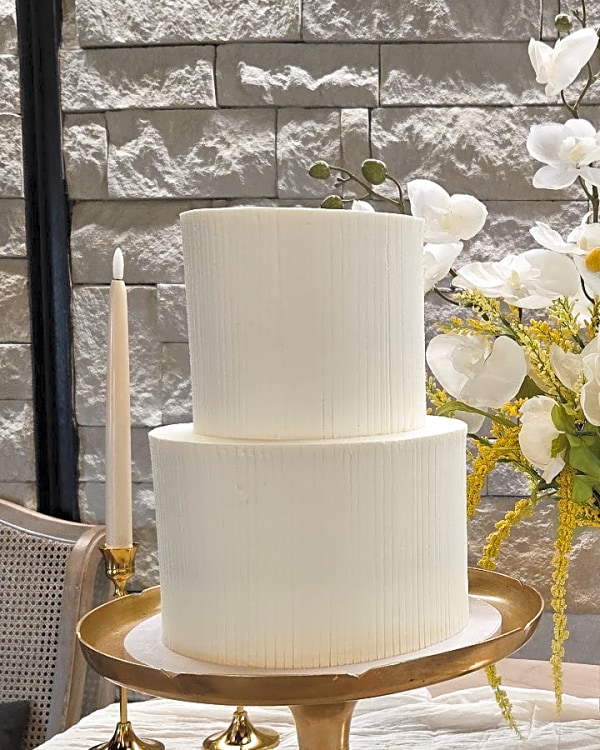 Wedding cake by Sweet E's Bakery in Lindon, two-tier buttercream wedding cake with vertical ribbed texture in off-white