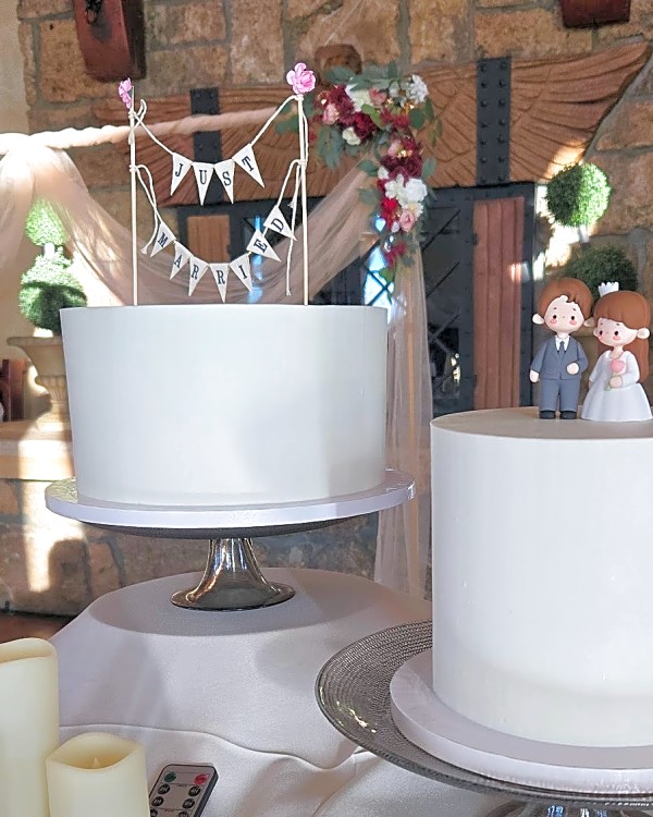 Two single-tier white wedding cakes, one with a Just Married banner topper