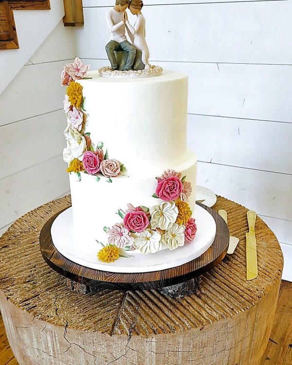 Walker Farms wedding cake, a two-tier white wedding cake with buttercream floral decorations in pink, yellow, and white