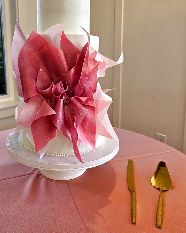 River Bridge wedding cake, three-tier round white buttercream cake with an abstract pink and red wafer paper flower and