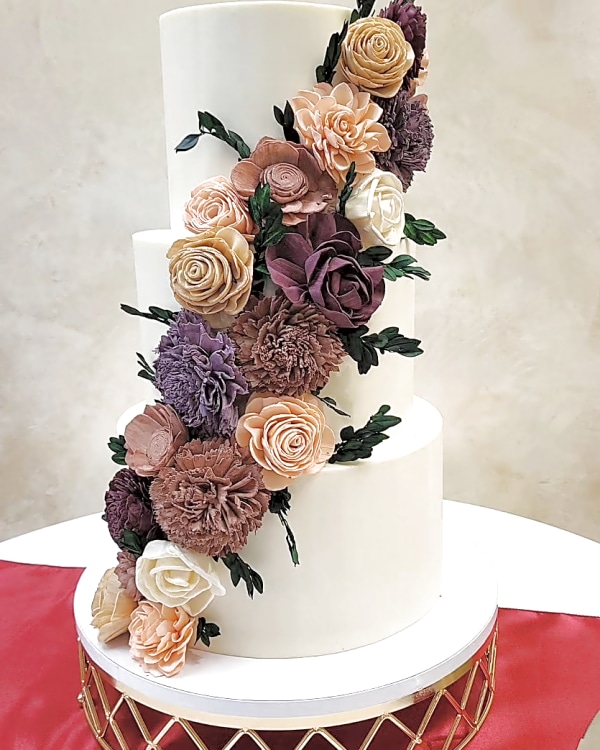 Wedding cake by Sweet E's Bakery in Mapleton, three-tier smooth white wedding cake with cascading blush, nude, and deep purple sugar flowers