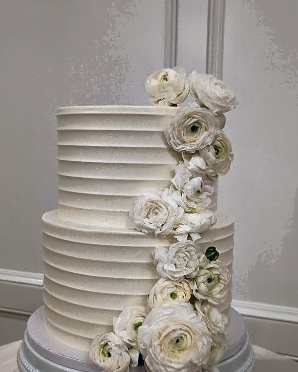 Twenty & Creek wedding cake, two-tier wedding cake with white horizontal buttercream ribbing and fresh white flowers cascading