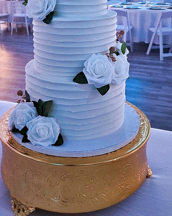 Twenty & Creek wedding cake, a four-tier wedding cake with horizontal textured buttercream, adorned with white roses and gold