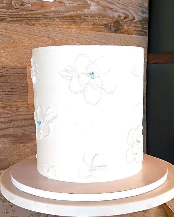 Wedding cake by Sweet E's Bakery in Heber City, one-tier buttercream wedding cake with white piped floral details and light blue bead accents