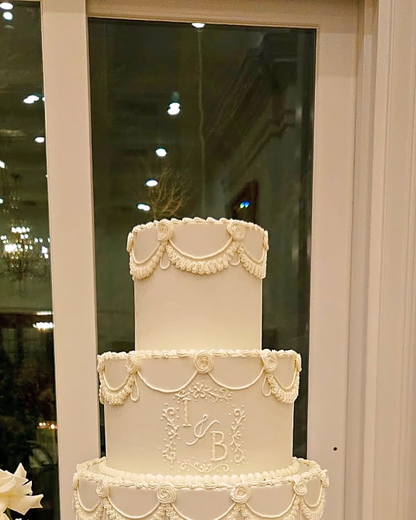 White wedding cake with scalloped piping and a piped monogram at Twenty and Creek, Sandy