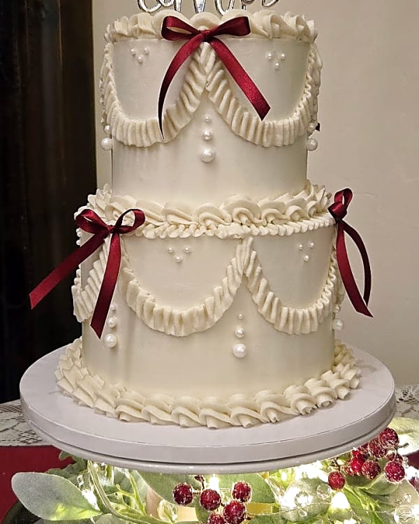Ivory wedding cake with piped swags, pearls and burgundy ribbon bows at The Lodge at Traverse Mountain, Lehi