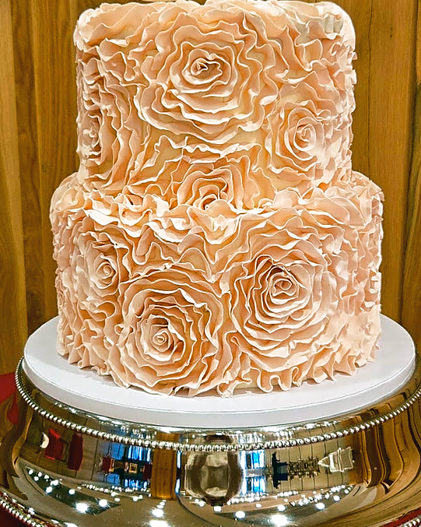 Two-tier blush buttercream wedding cake covered in piped ruffle rosettes at Snowpine Lodge