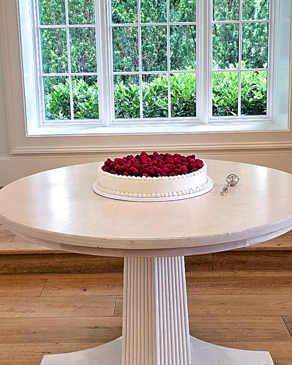 Small single-tier wedding cake topped with raspberries at Twenty and Creek