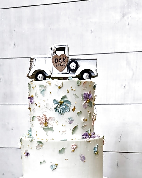 Walker Farms wedding cake, two-tier buttercream cake with palette knife flowers in pastel colors and gold leaf accents, topped