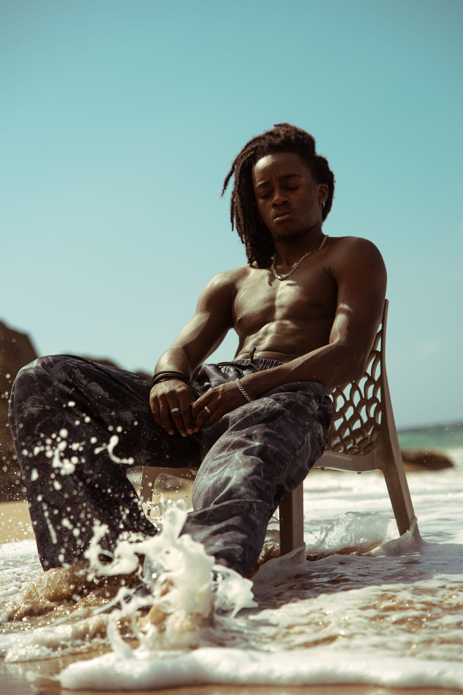 Mathys assis sur une chaise, une vague vient frapper ses pieds