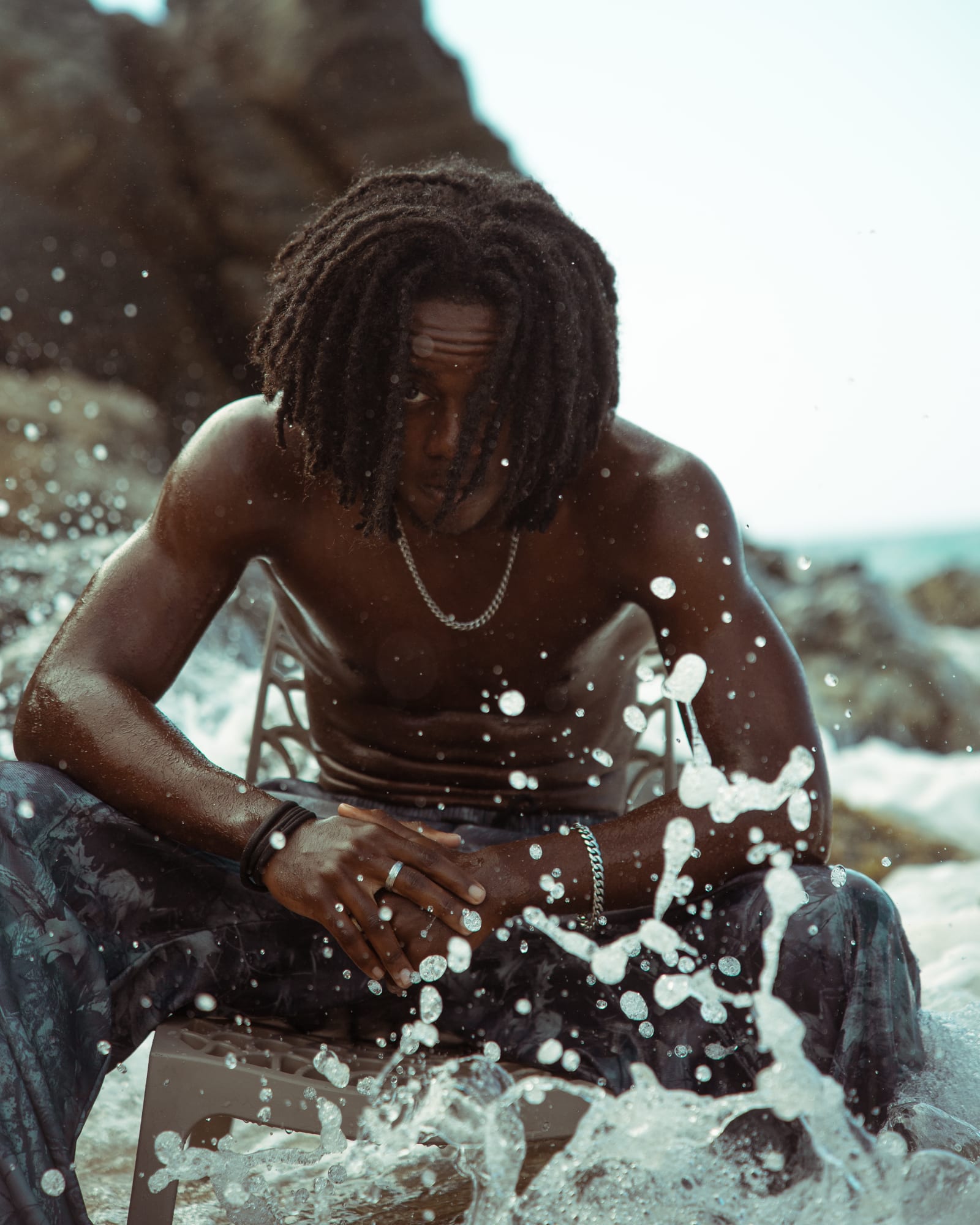 Mathys assis dans les vagues, gouttes d'eau en suspension
