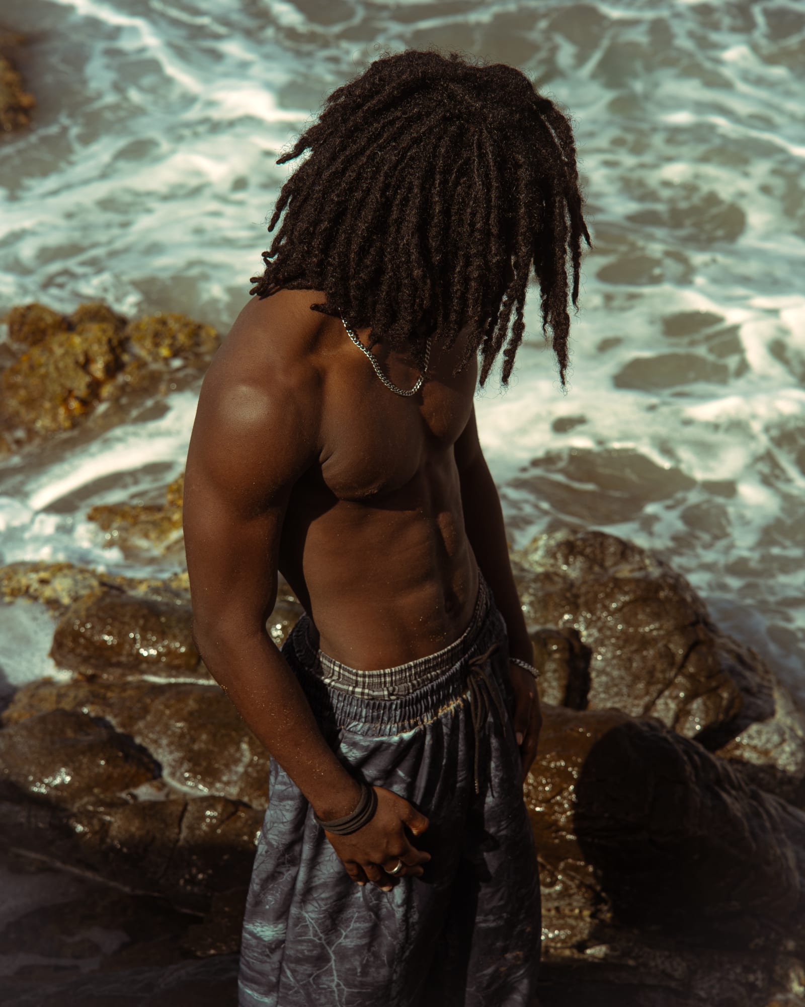 Mathys de profil sur les rochers, vagues en arriere-plan